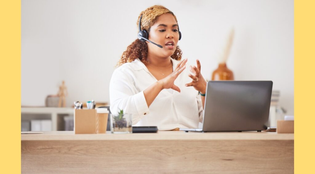 Commerciale devant son ordinateur passant un appel téléphonique à un client